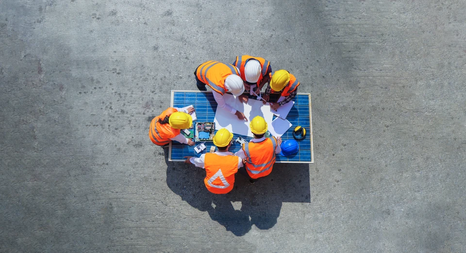 Intérieur industriel avec électricien en vêtements haute visibilité et casque orange travaillant sur installation électrique murale