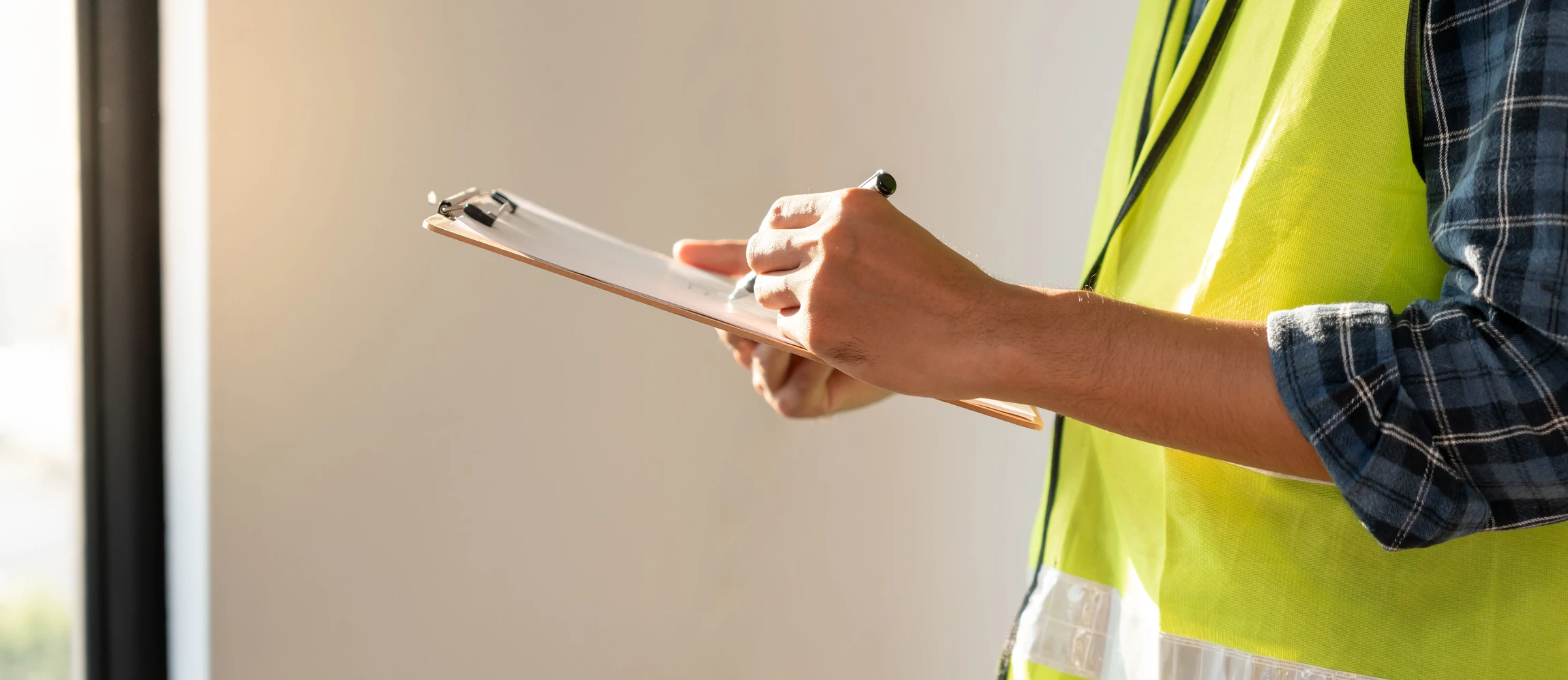 Électricien professionnel en tenue de travail bleue installant une prise électrique murale dans un intérieur résidentiel