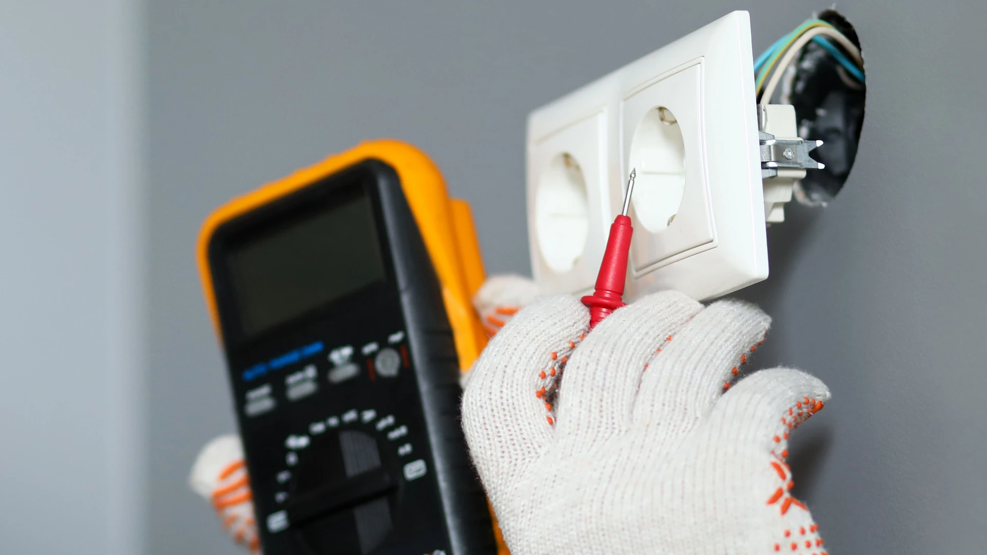 Électricien professionnel effectuant des mesures électriques dans un intérieur résidentiel