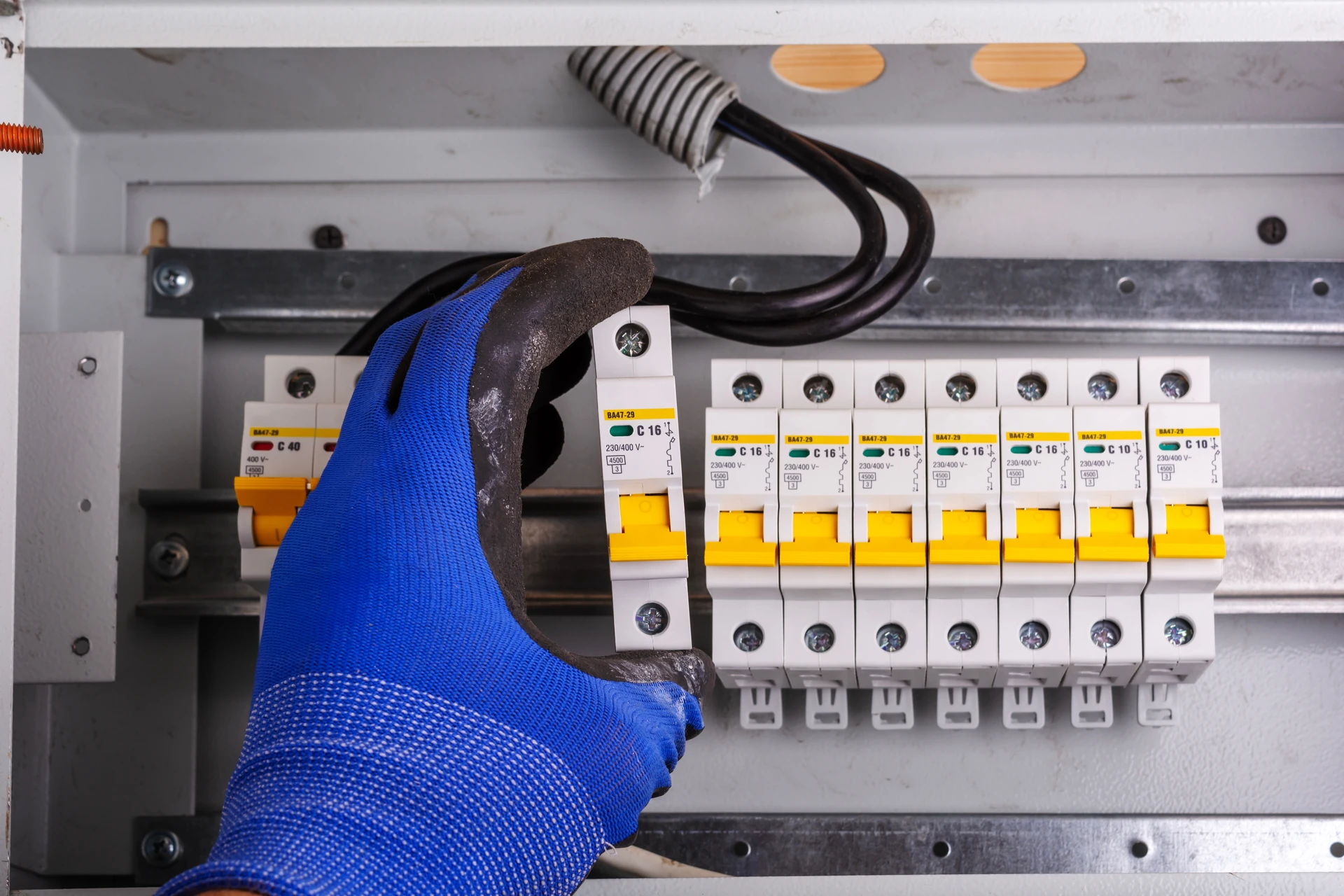 Électricien professionnel portant un casque de sécurité effectue des mesures électriques sur une prise murale résidentielle à l'aide d'un multimètre numérique